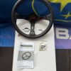 Avtosh black leather sport steering wheel shown with its box, instruction booklet and visible accessories.
