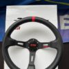 Front product view of the black Avtosh steering wheel with red centre marker and branded centre button.