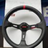 Front close-up of the black leather Avtosh three-spoke sport steering wheel with red centre marker.
