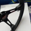 Close-up of the black leather rim, stitching, spoke opening and Avtosh branding.